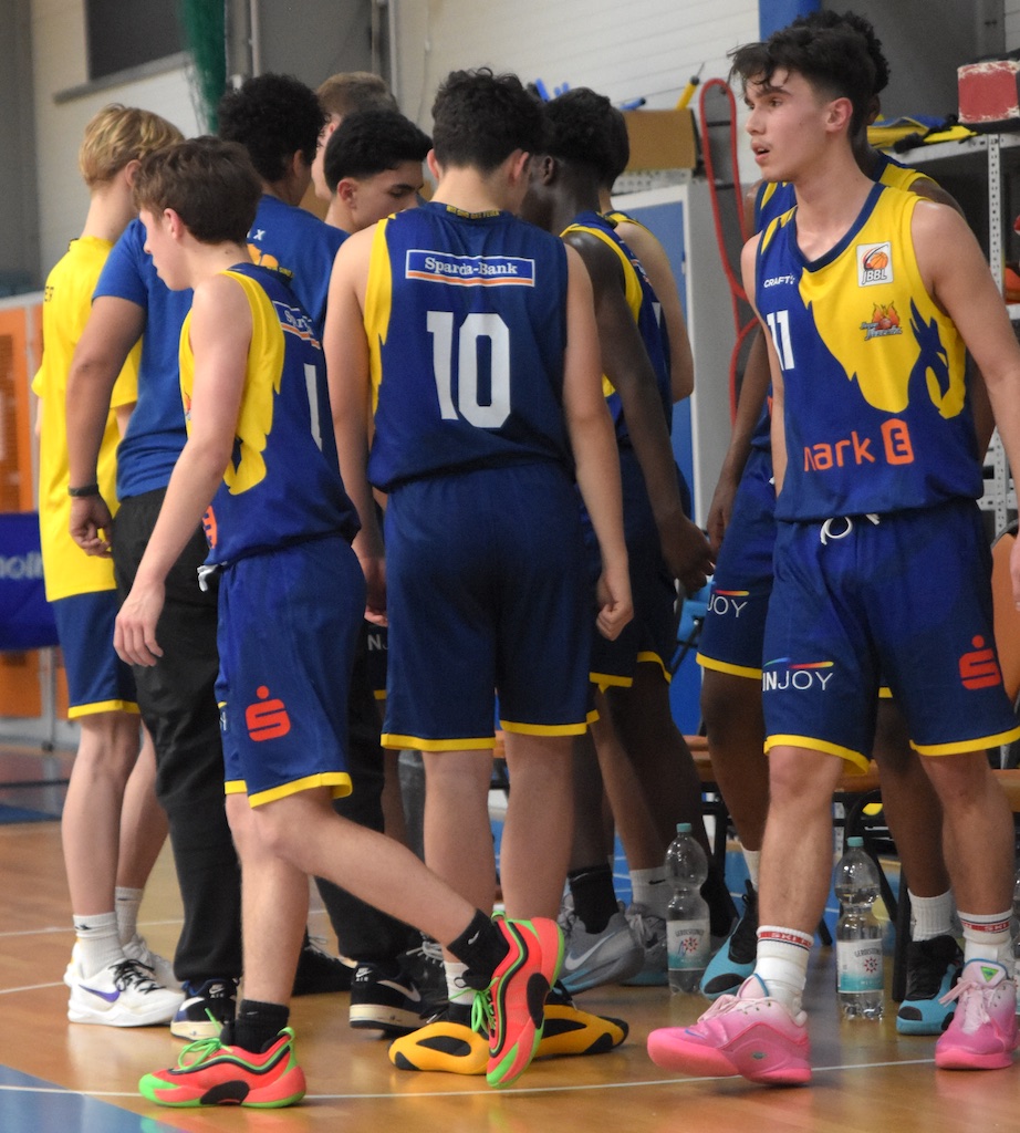 Eine Gruppe junger Basketballspieler in blauen Trikots auf dem Spielfeld.
