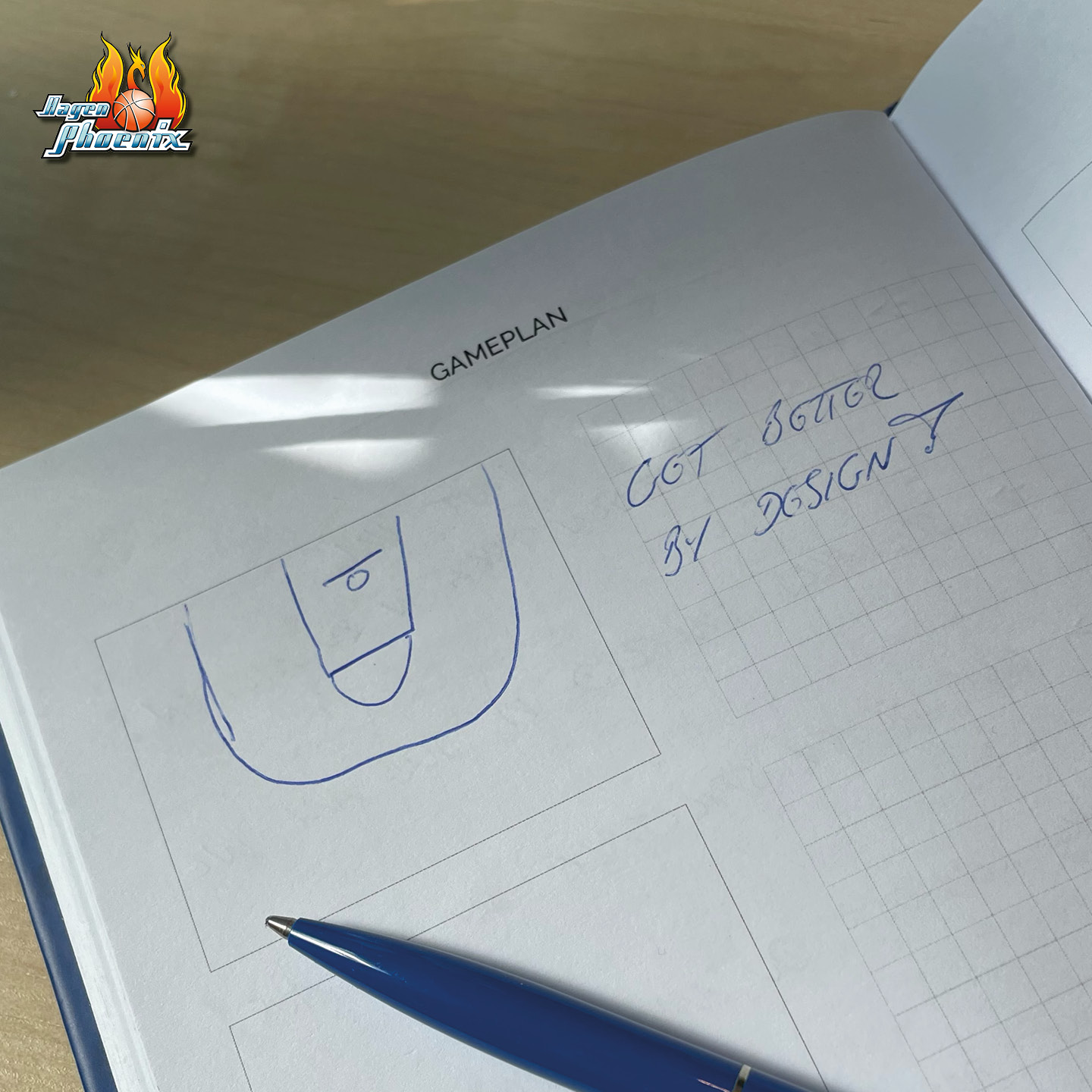 Offenes Notizbuch mit Basketballspielfeld-Zeichnung und handschriftlicher Notiz neben blauem Stift.