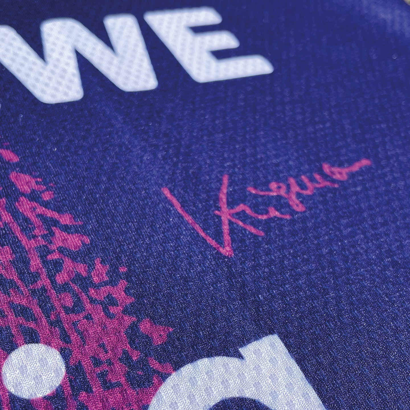 Signierte Sportbekleidung in Blau und Pink mit roter Unterschrift.