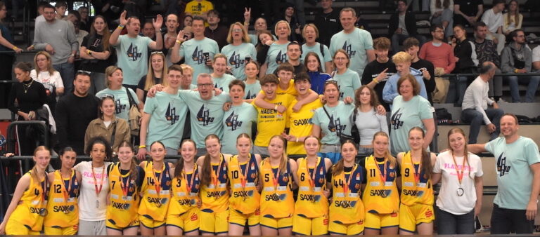 Eine lachende Gruppe von Basketballspielern in gelben Trikots mit Fans in blauen T-Shirts.