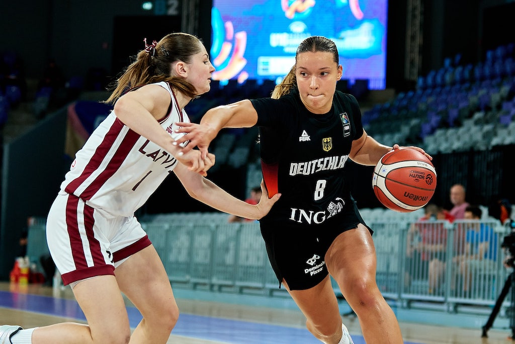 Zwei Basketballspielerinnen kämpfen intensiv um den Ball auf dem Spielfeld.