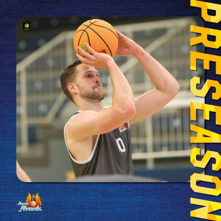 Ein Basketballspieler wirft konzentriert einen orangefarbenen Ball im Spiel.