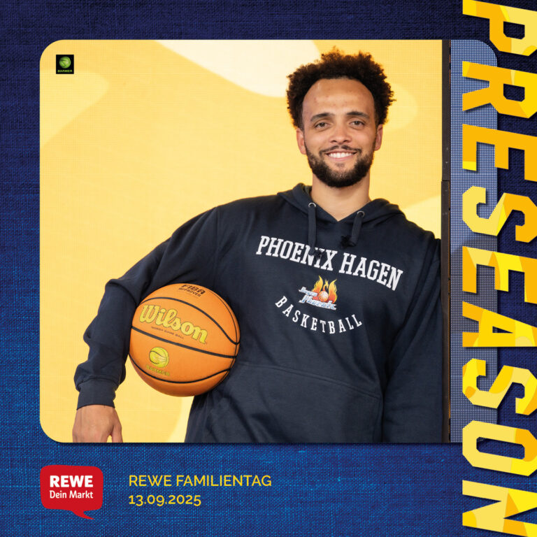 Ein Mann mit lockigem Haar lächelt, hält einen Basketball im Arm, trägt ein dunkles Hoodie.