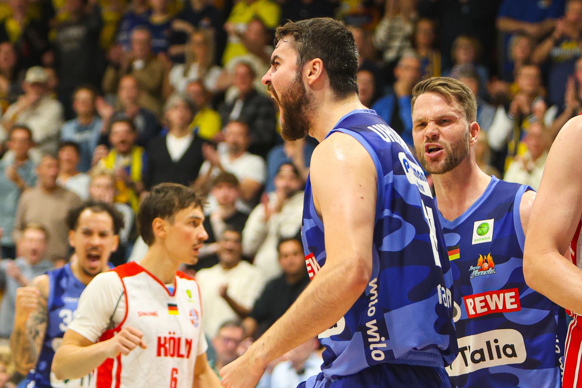 Basketballspieler in blauem Trikot jubeln leidenschaftlich auf dem Spielfeld