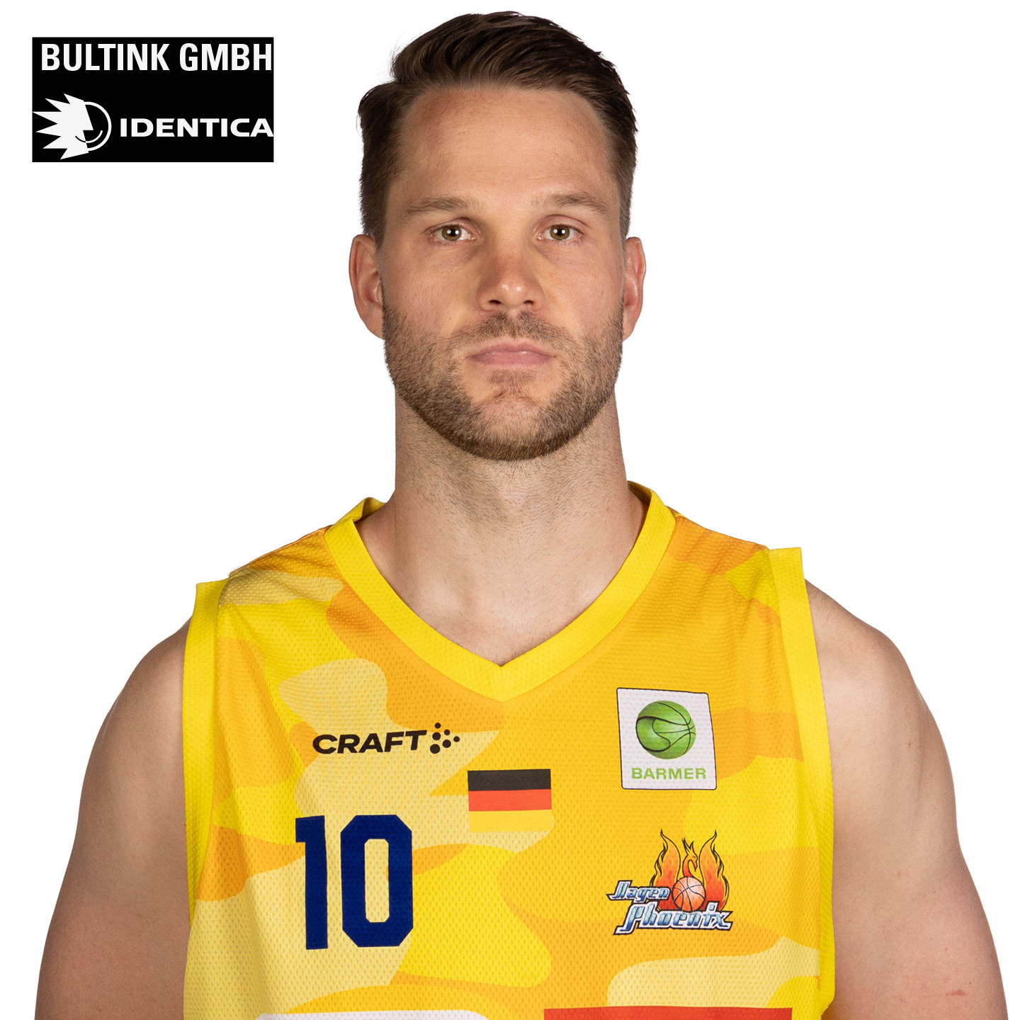 Ein Mann im Basketballtrikot schaut ernst; leuchtendes Gelb mit bunten Logos.