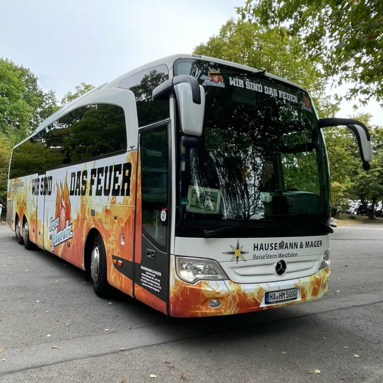 Ein Reisebus mit feuriger Dekoration, der auf einem Parkplatz steht.