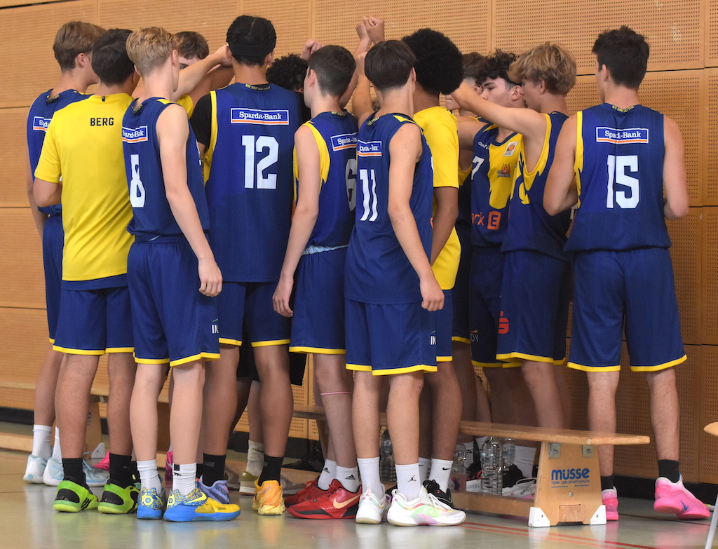Mehrere junge Basketballspieler in blauen und gelben Trikots stehen dicht zusammen.