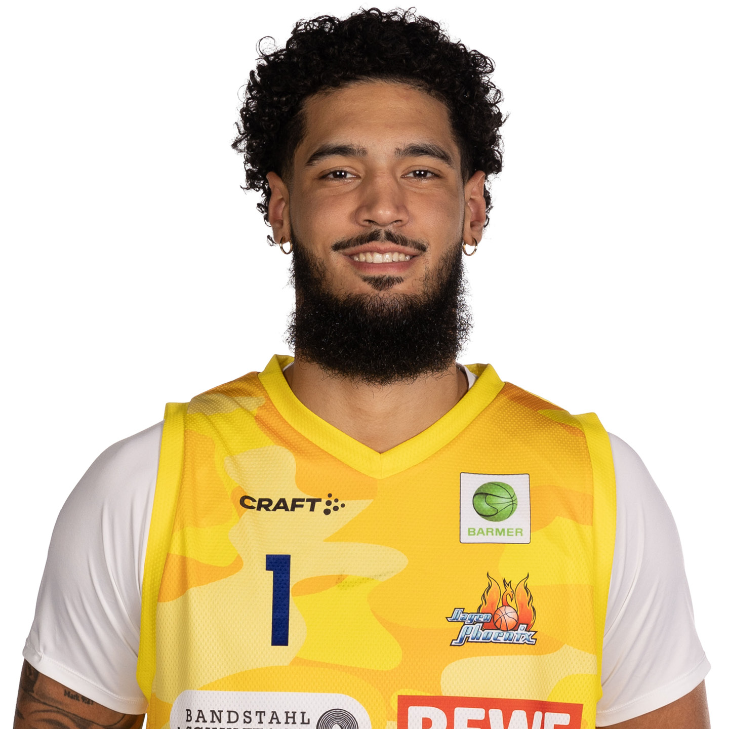 Ein lächelnder Mann mit lockigem Haar in gelbem Basketballtrikot.