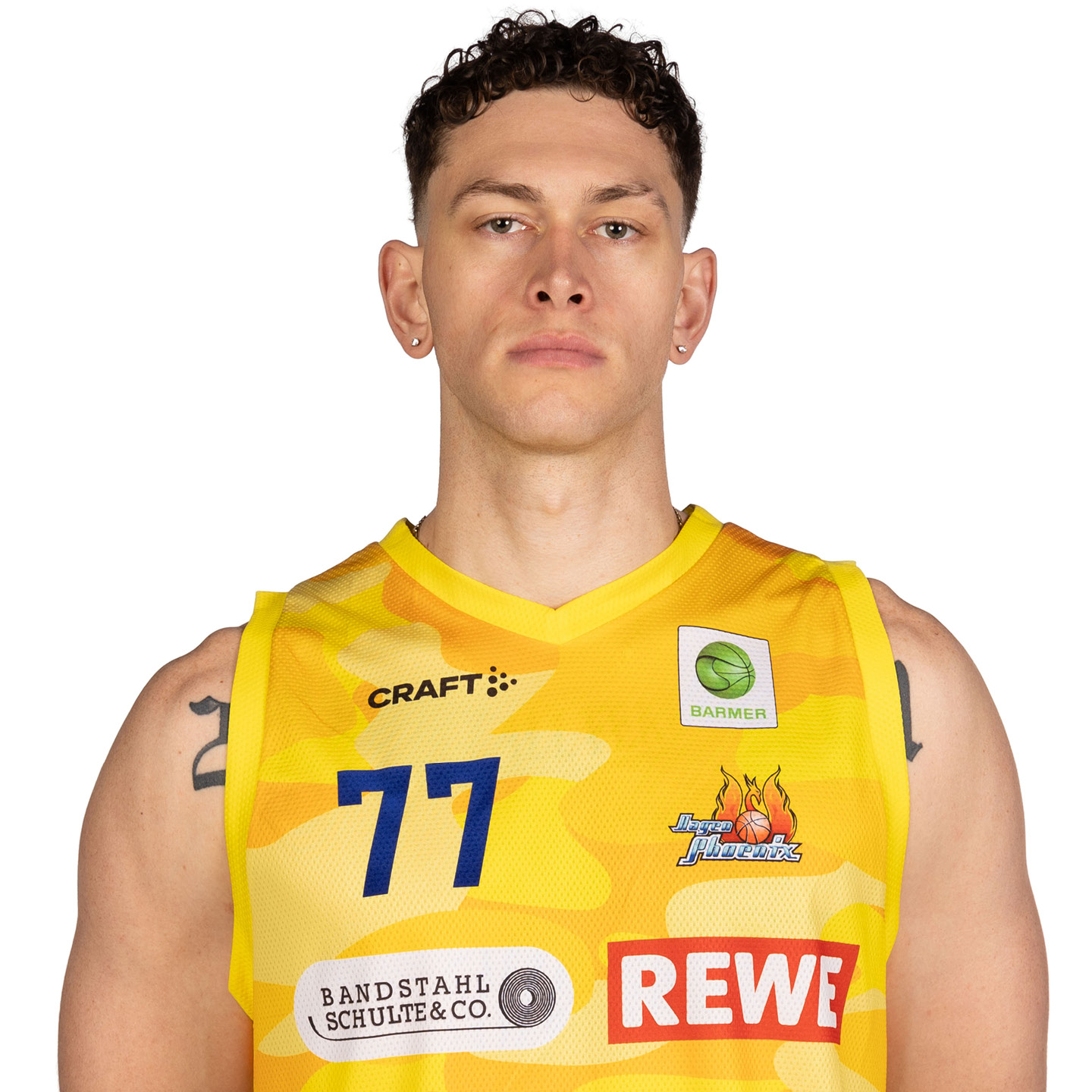 Ein Mann in einem gelben Basketballtrikot, ernst blickend, mit lockigem Haar.