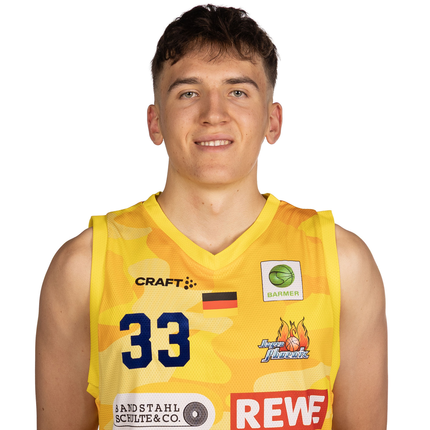 Ein junger Mann lächelt in einem gelben Basketballtrikot mit Logos.