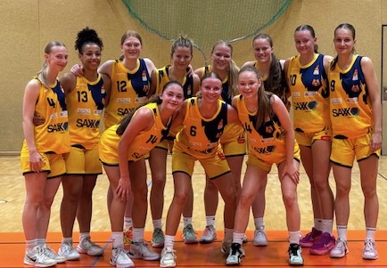 Eine Gruppe von jungen Frauen in gelben Basketballtrikots lächelt in die Kamera