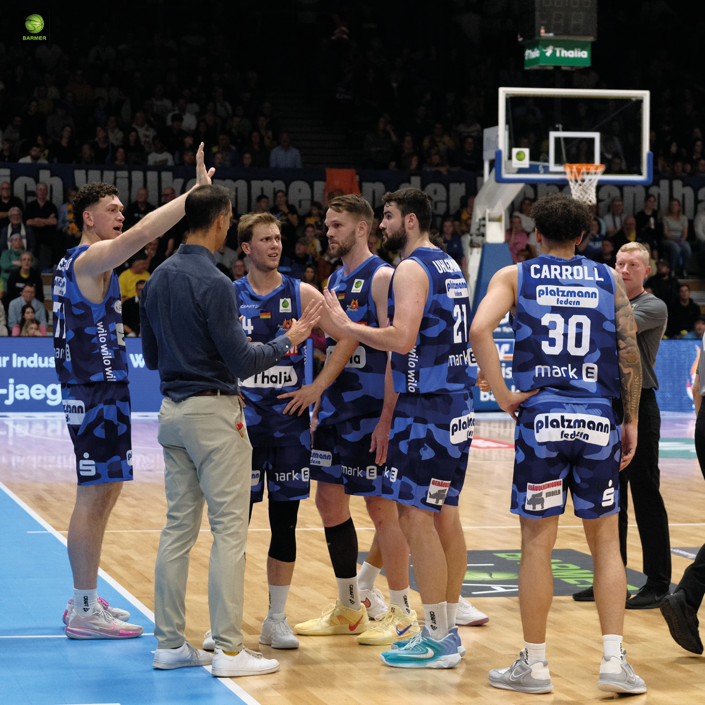 Eine Basketballmannschaft in blauen Trikots versammelt sich zur Beratung.