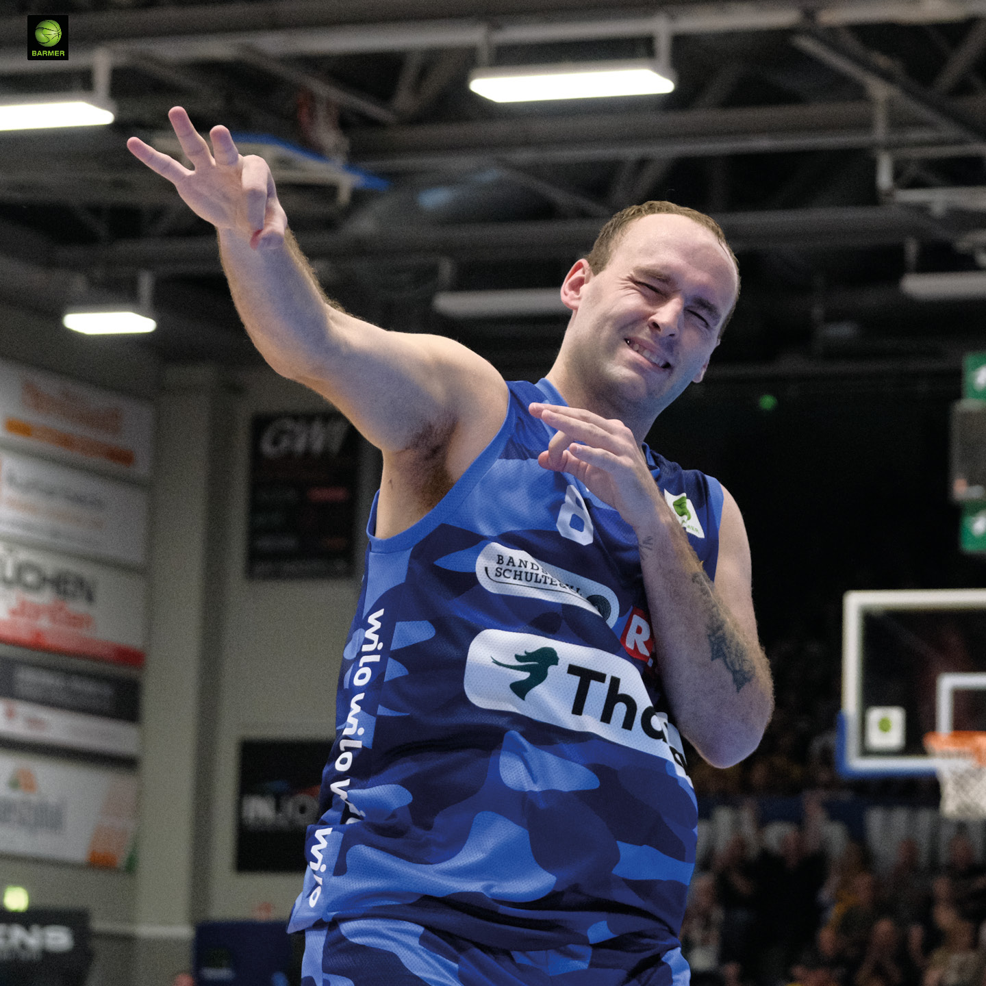 Ein Basketballspieler in blauem Trikot posiert mit humorvollem Ausdruck.
