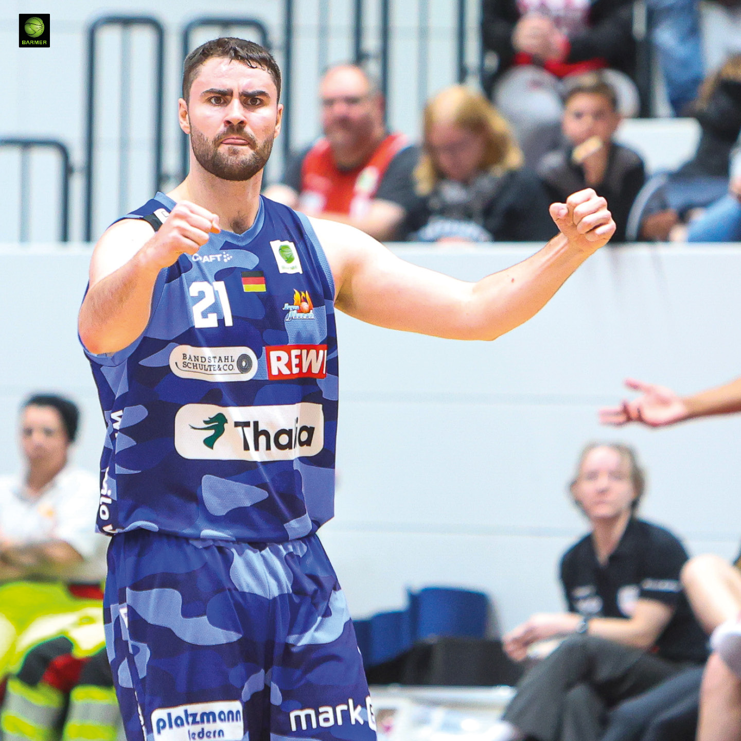 Ein Basketballspieler im blauen Trikot jubelt kraftvoll mit erhobenen Fäusten