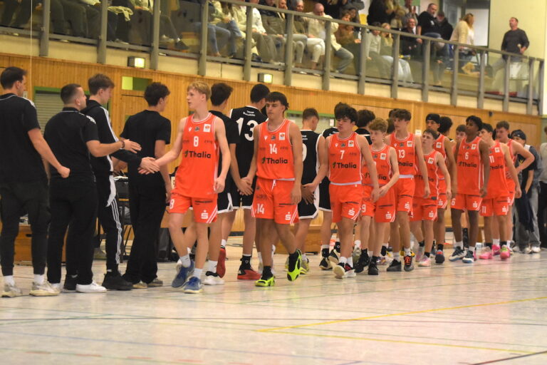 Basketballteam in auffälligen orangefarbenen Trikots gibt freundlich Handschlag nach Spiel