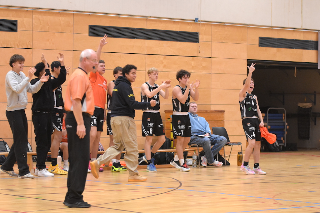 Eine Gruppe von Basketballspielern jubelt am Spielfeldrand voller Begeisterung