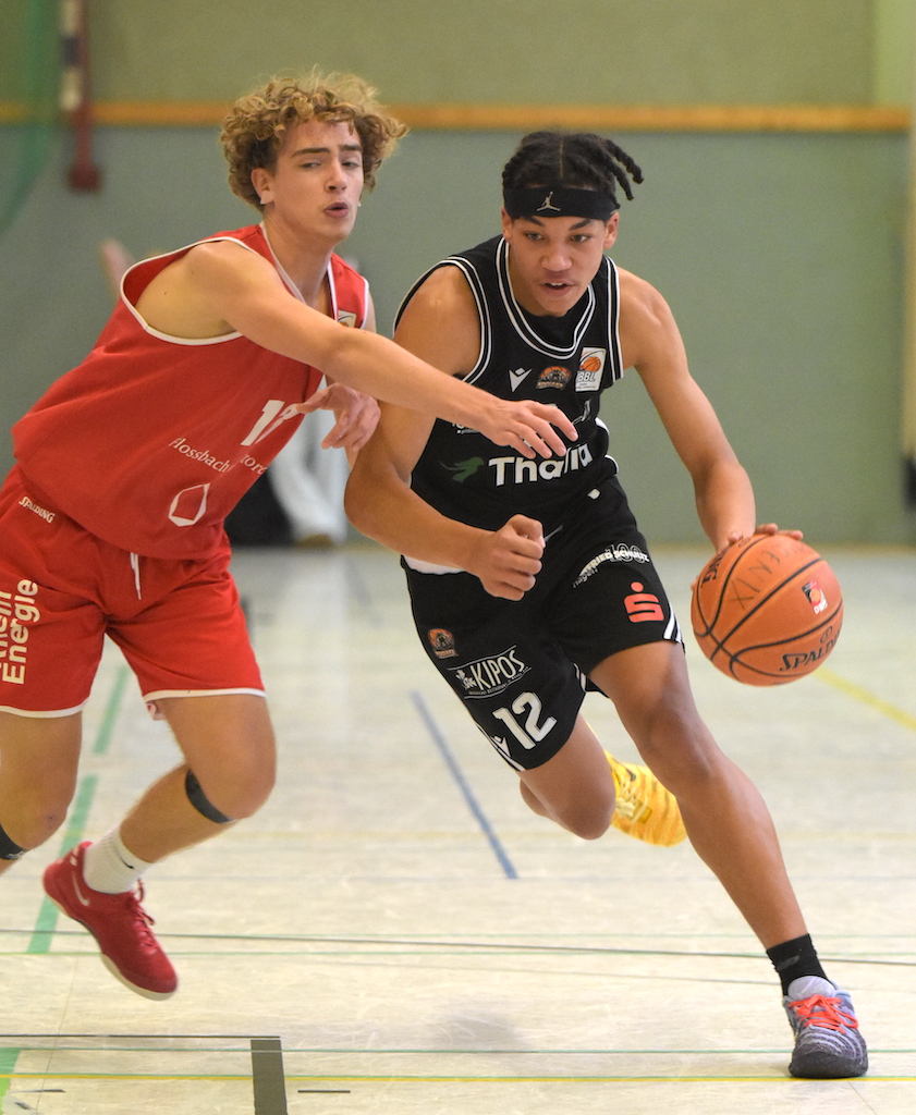 Zwei junge Basketballspieler mit entschlossenen Gesichtern im Zweikampf auf dem Feld