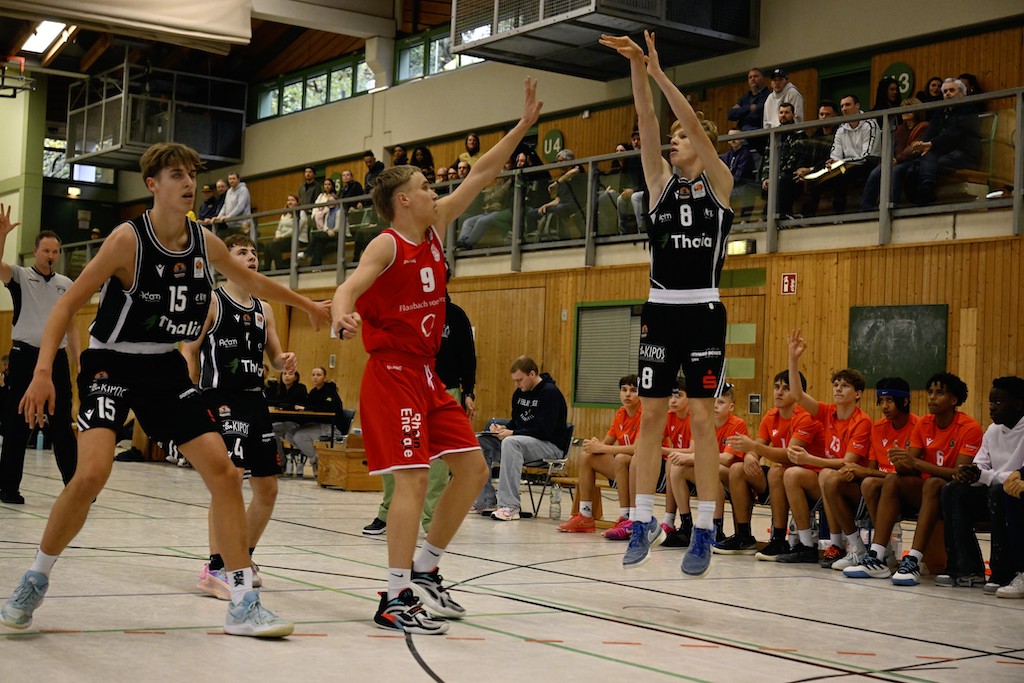 Junge Basketballspieler mit entschlossenem Gesichtsausdruck im Spiel in heller Sporthalle