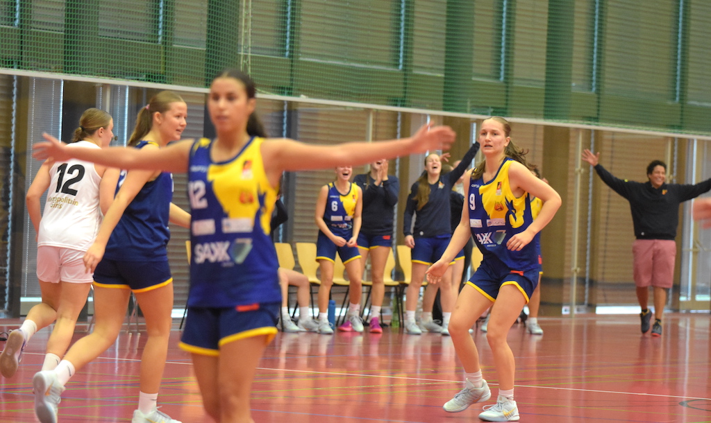 Frauen Basketballspiel gelbe und blaue Trikots Freude konzentrierte Gesichter rote Halle