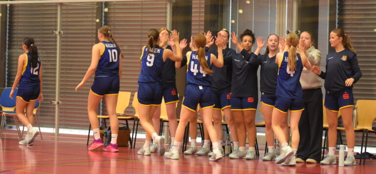 Mehrere junge Frauen im blauen Basketballtrikot geben sich freudig ein High Five