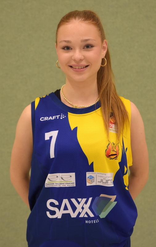 Junge Frau mit langen roten Haaren lacht freundlich im blauen Basketballtrikot Nummer 7