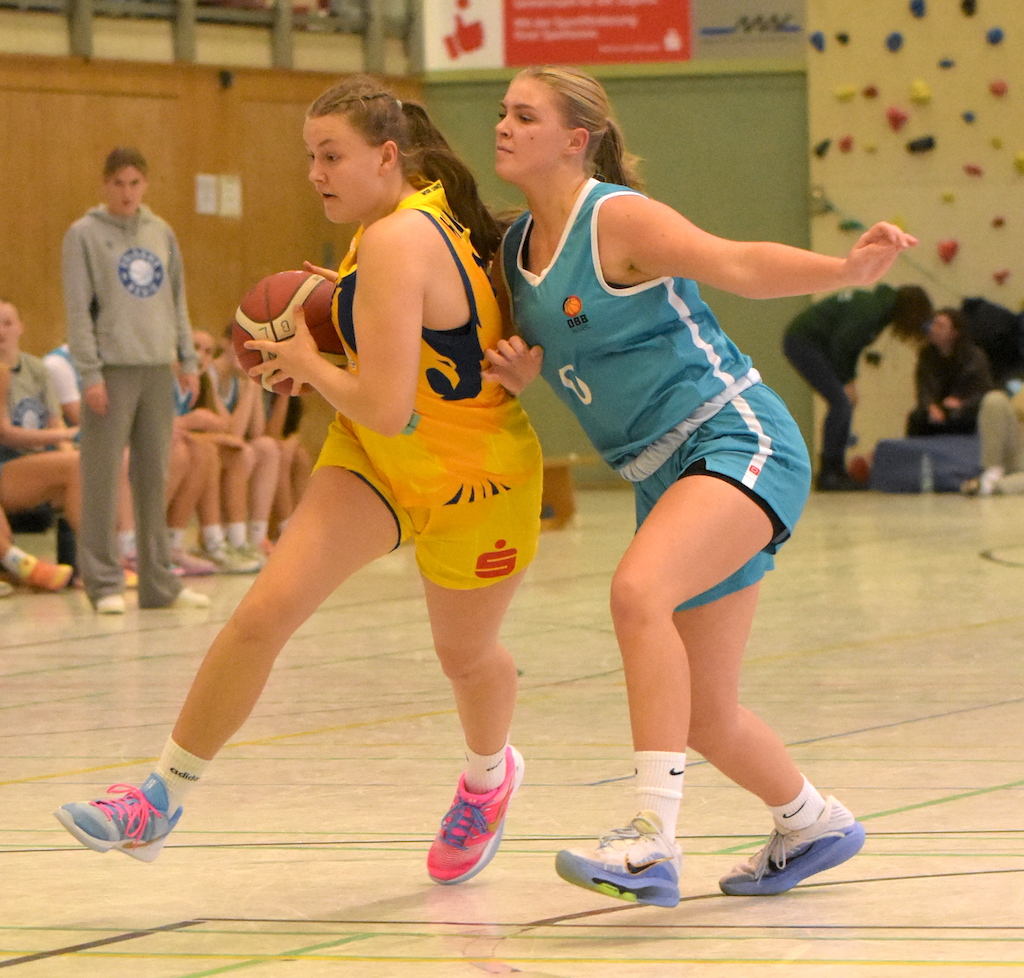 Zwei junge Basketballspielerinnen kämpfen konzentriert, dynamisch und sportlich um den Ball