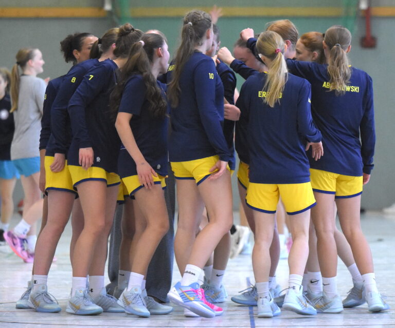 Eine Gruppe junger Frauen in gelb-blauer Sportkleidung feuert sich beim Handball an