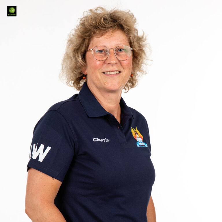 Frau mit lockigem blondem Haar und Brille lächelt freundlich im blauen Poloshirt