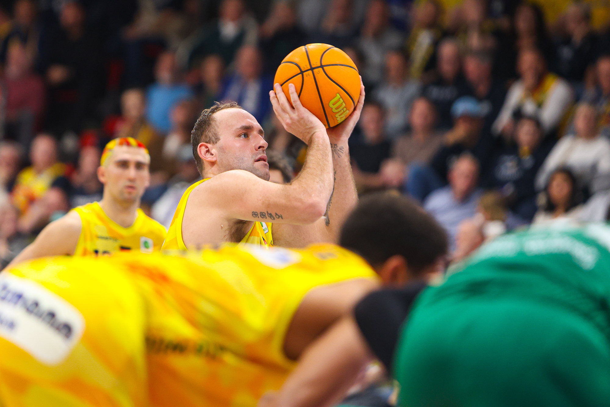 Ein konzentrierter Basketballspieler im gelben Trikot bereitet einen Freiwurf vor
