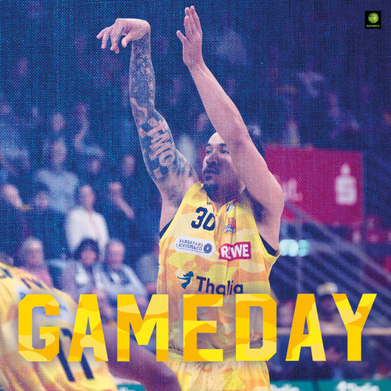 Ein Basketballspieler mit tätowiertem Arm wirft konzentriert einen Ball im gelben Trikot