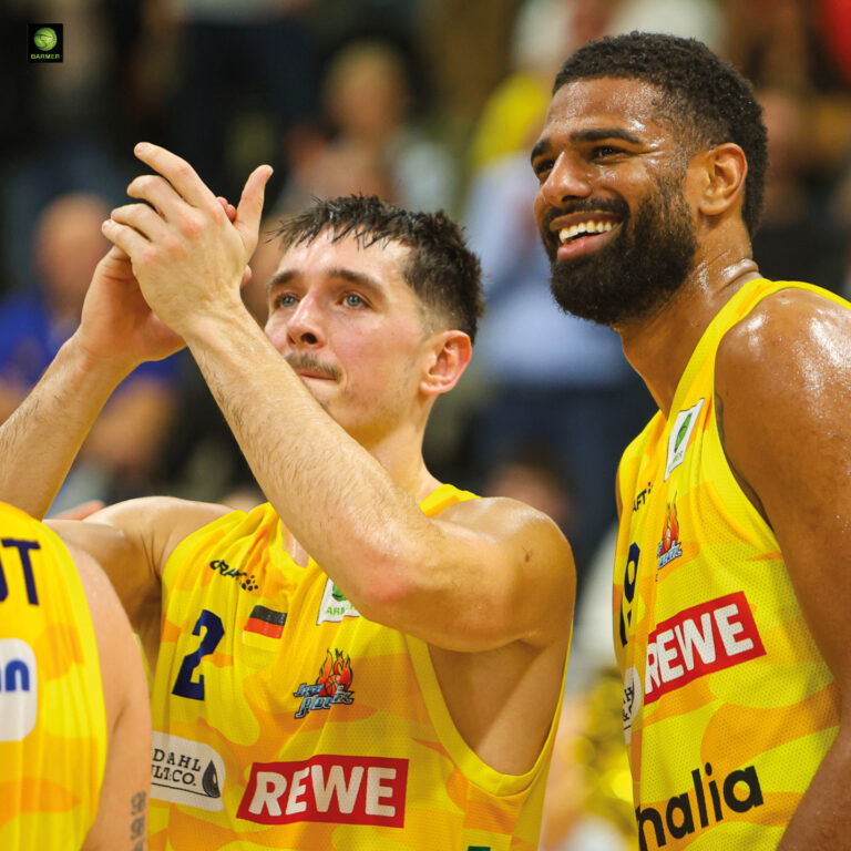 Zwei Basketballspieler im gelben Trikot jubeln glücklich und klatschen Beifall