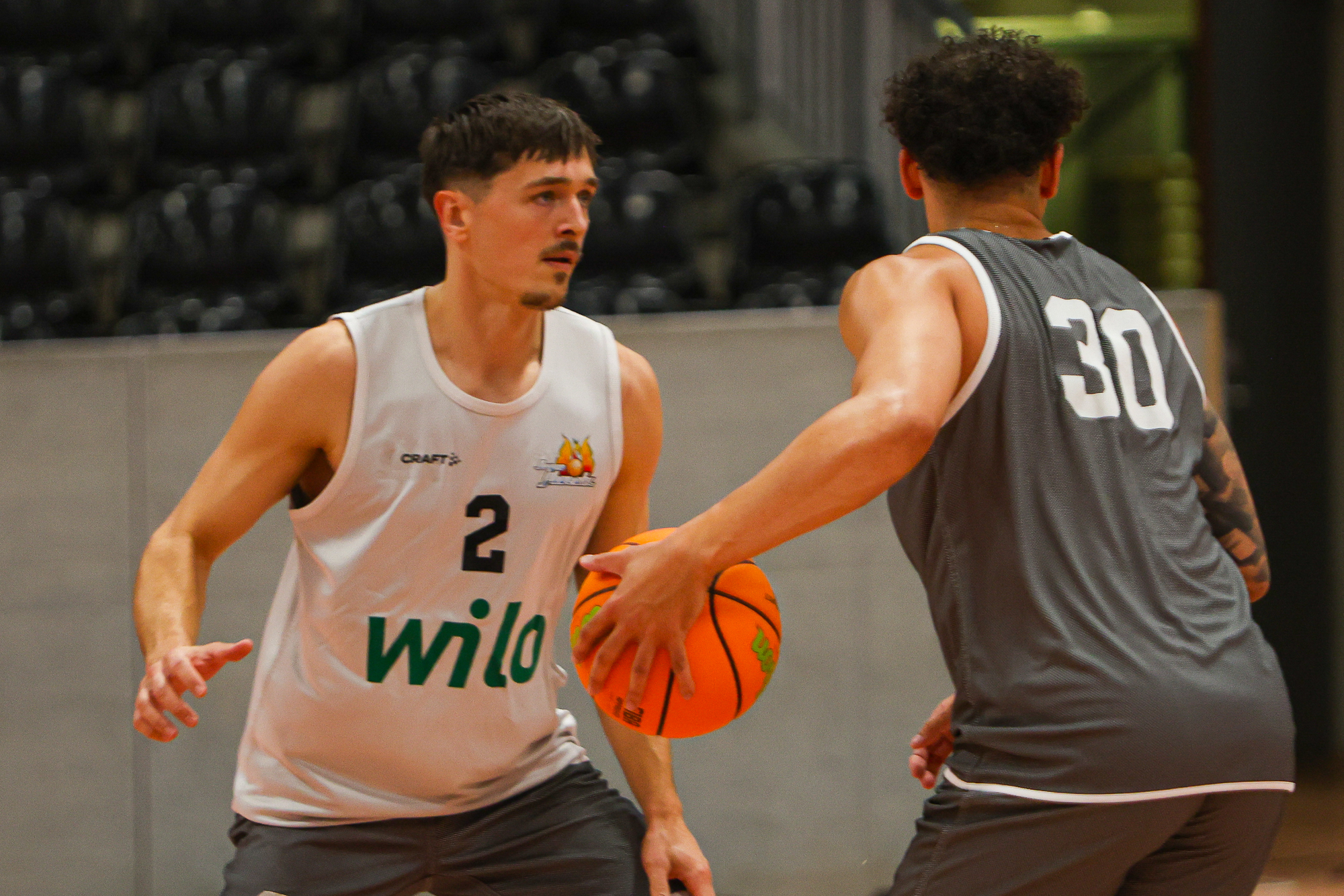 Zwei junge Männer beim Basketballspiel, einer mit Ball, beide konzentriert in grauen Trikots