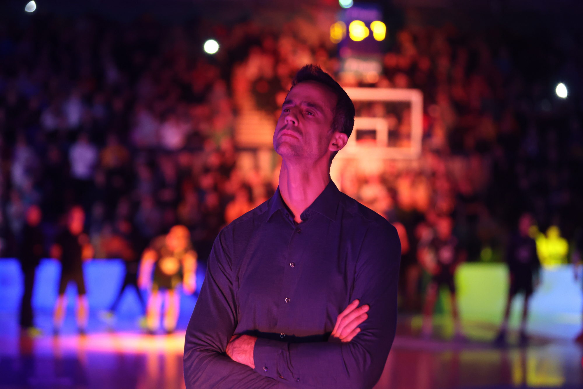 Ein Mann mit nachdenklichem Gesichtsausdruck steht auf einer bunt beleuchteten Bühne