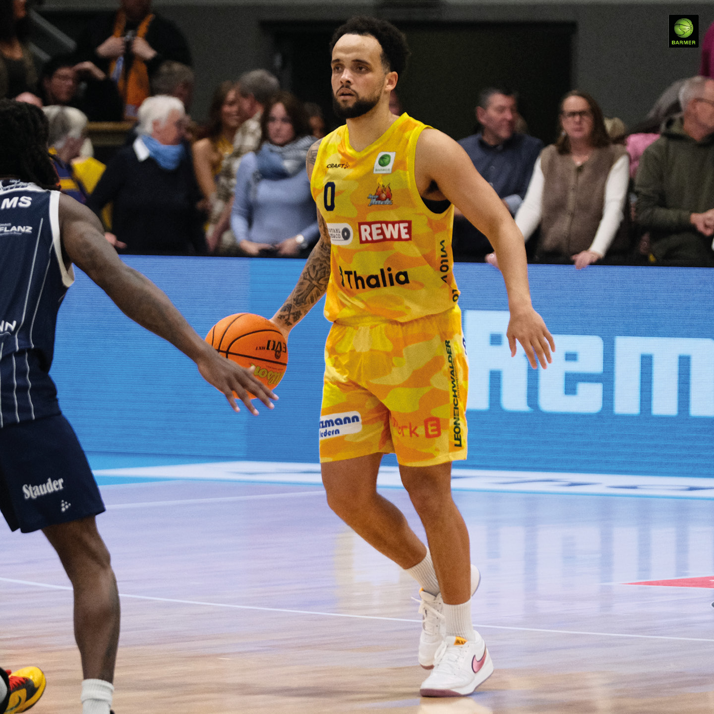 Ein fokussierter Basketballspieler im gelben Trikot hält einen orangefarbenen Ball