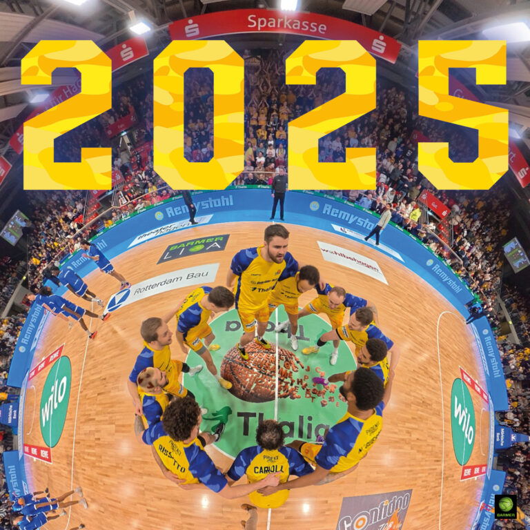 Mehrere jubelnde Handballspieler im gelben Trikot um eine Torte und große gelbe 2025