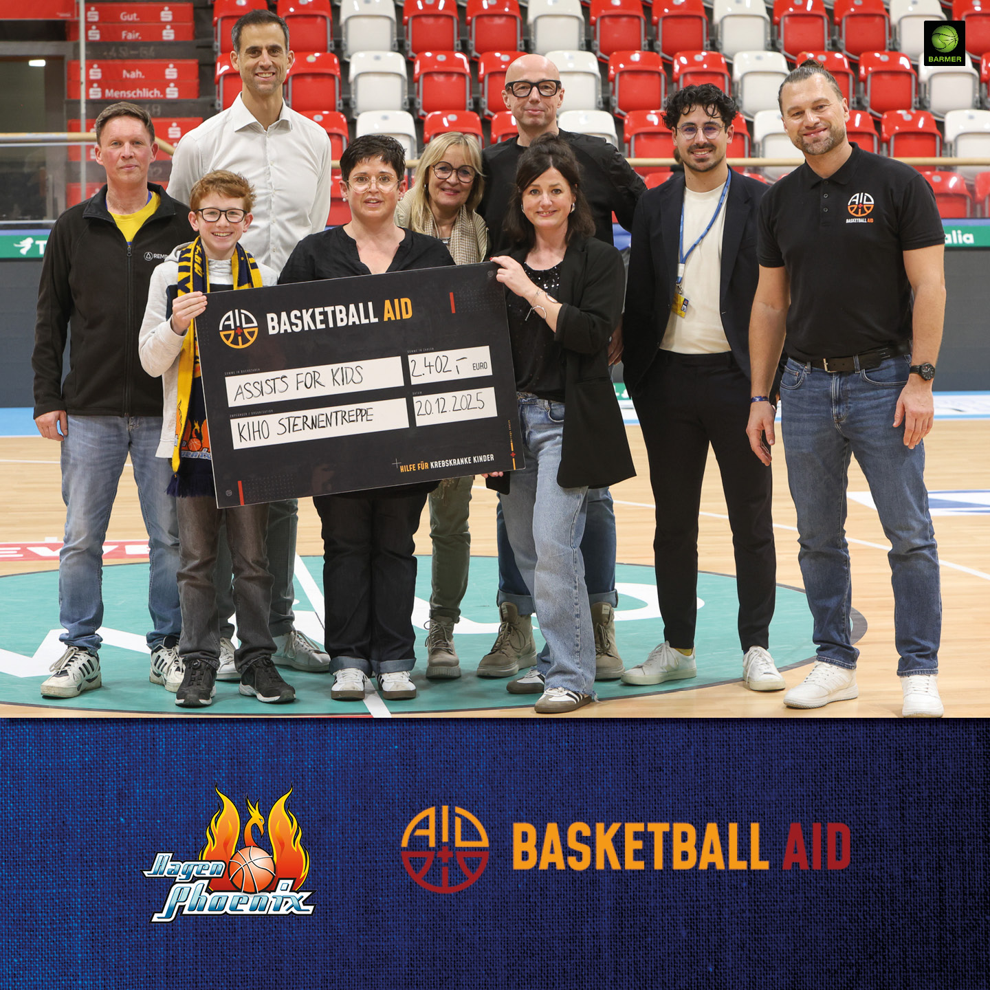 Eine gemischte Gruppe lachender Menschen hält einen großen Scheck auf einem Basketballfeld