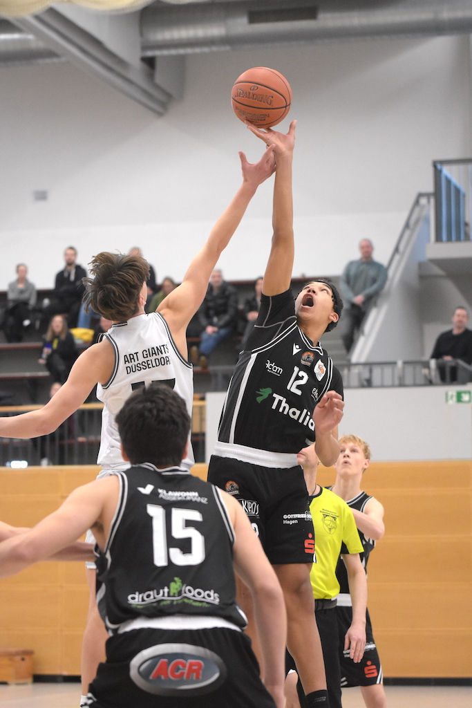Zwei Basketballspieler in Schwarz und Weiß springen entschlossen beim Sprungball hoch