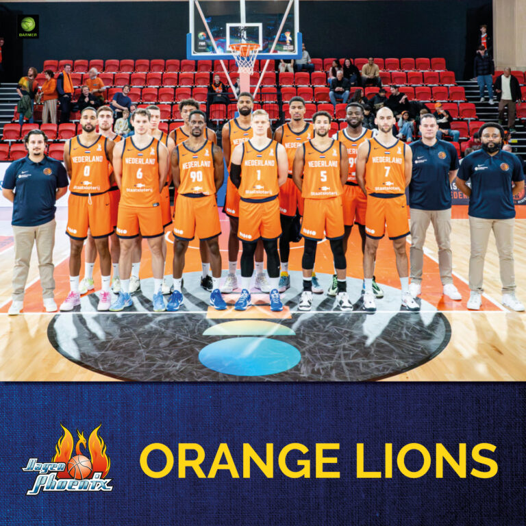 Eine niederländische Basketballmannschaft posiert lächelnd in orangefarbenen Trikots auf dem Spielfeld