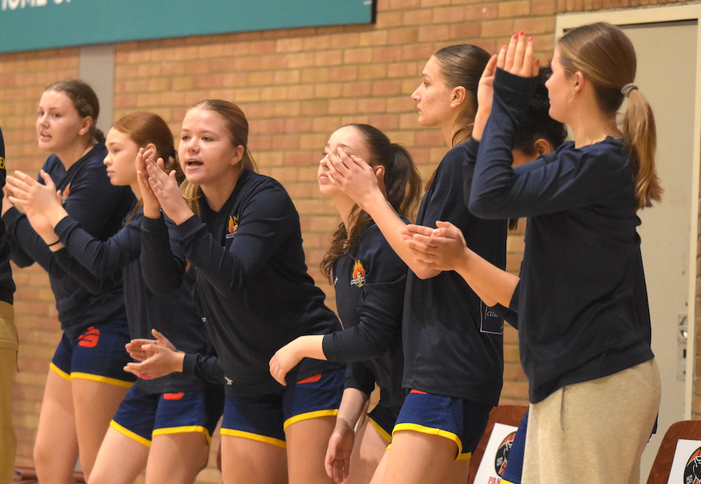 Sechs junge Frauen in dunkelblauen Sportoutfits feuern ihr Team energisch an