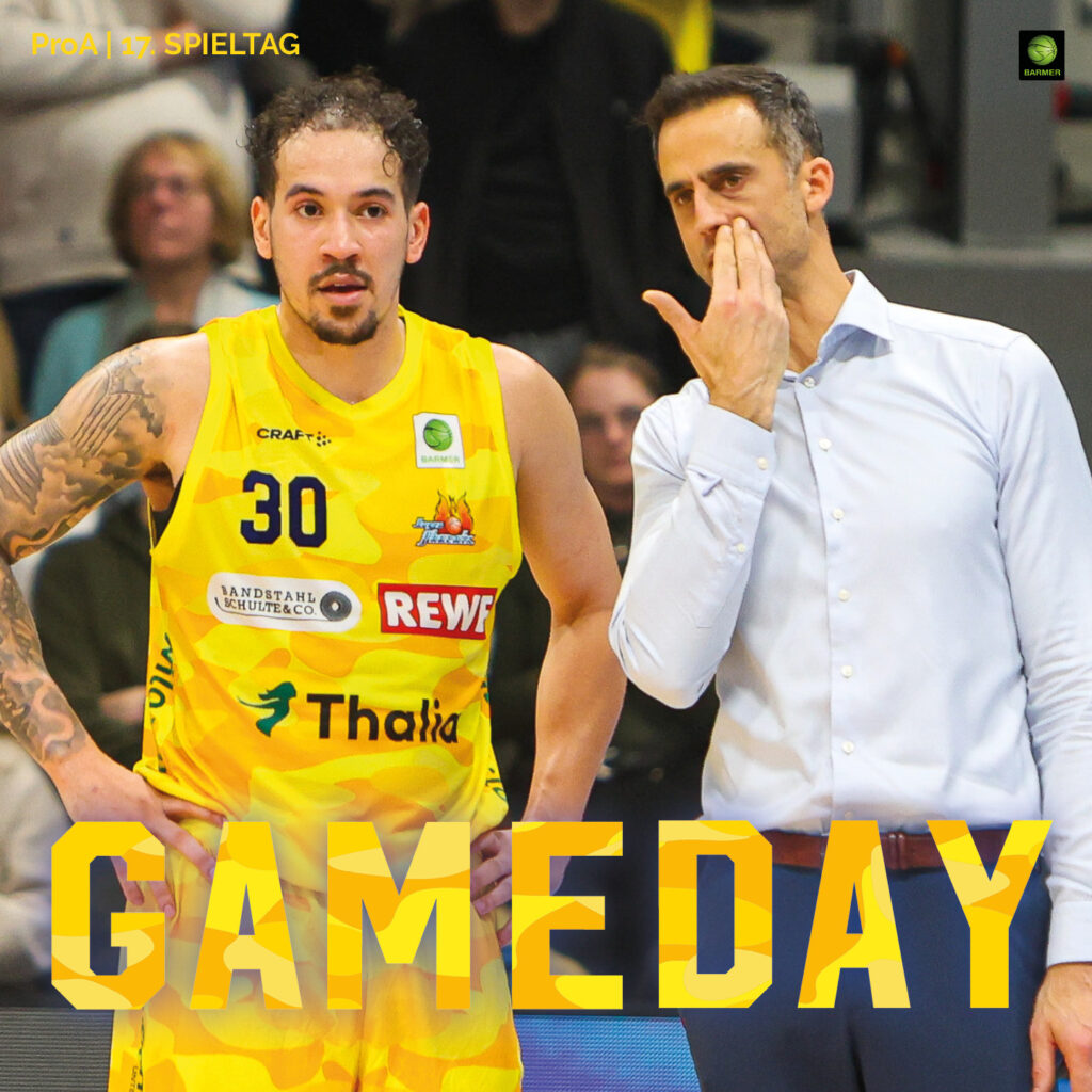 Zwei Männer im gelben Basketballtrikot und im Anzug reden angespannt am Spielfeldrand