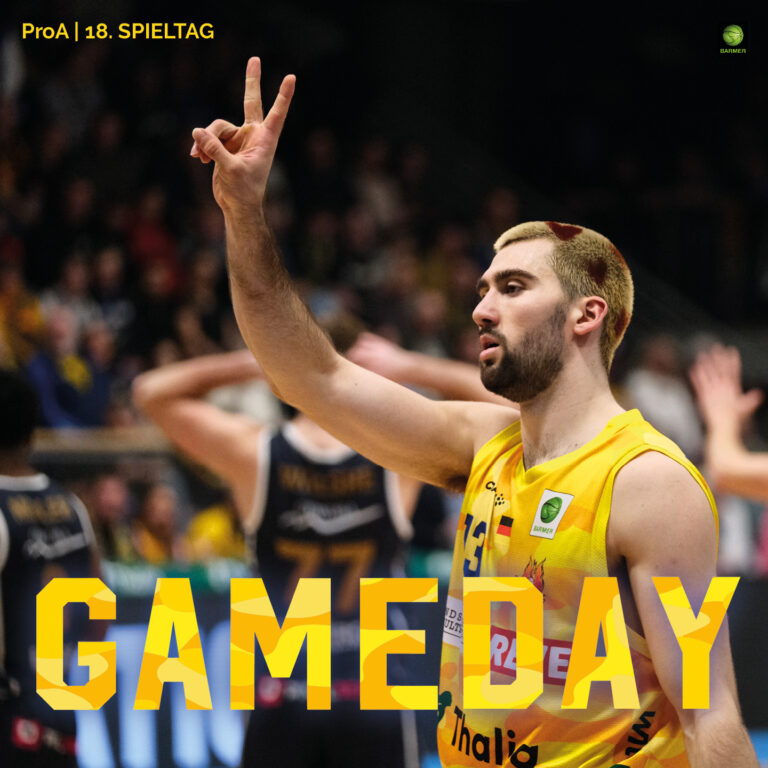 Mann im gelben Basketballtrikot zeigt mit ernster Miene zwei Finger zum Sieg