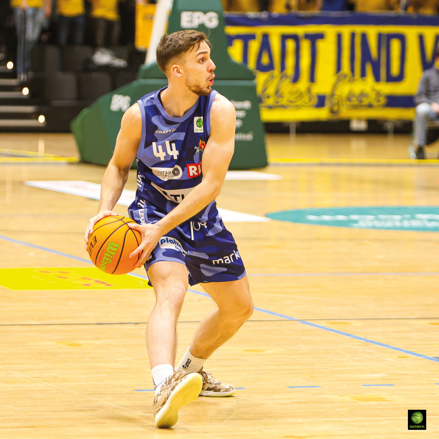 Ein junger Basketballspieler im blauen Trikot konzentriert sich mit Ball auf dem Feld