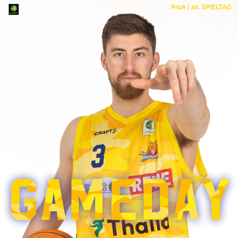 Ein junger Mann mit braunen Haaren und Bart lächelt selbstbewusst im gelben Basketballtrikot und zeigt entschieden auf den Betrachter