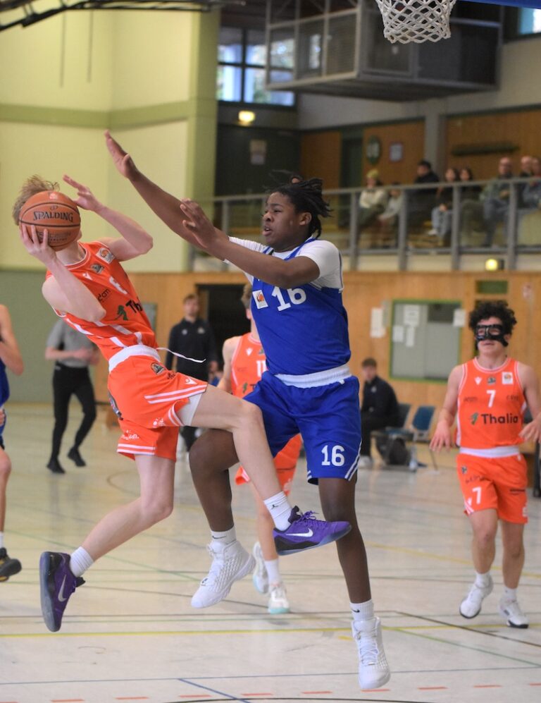 Zwei Basketballspieler, einer in Orange und einer in Blau, kämpfen intensiv um den Ball