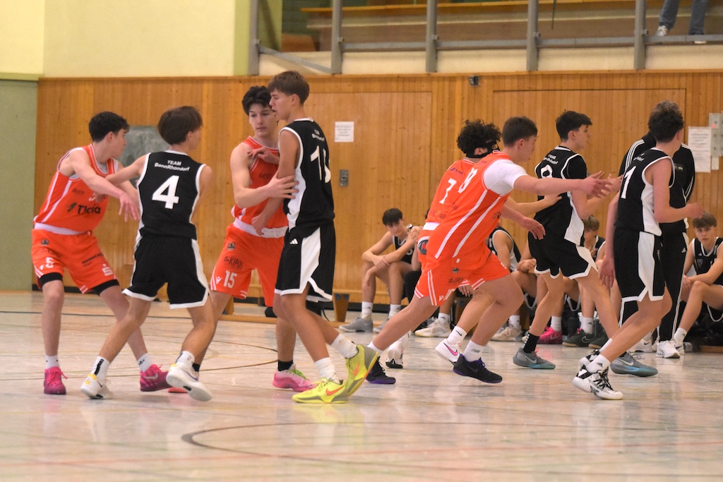 Mehrere Jugendliche spielen Basketball in einer Halle, sie wirken konzentriert und aktiv