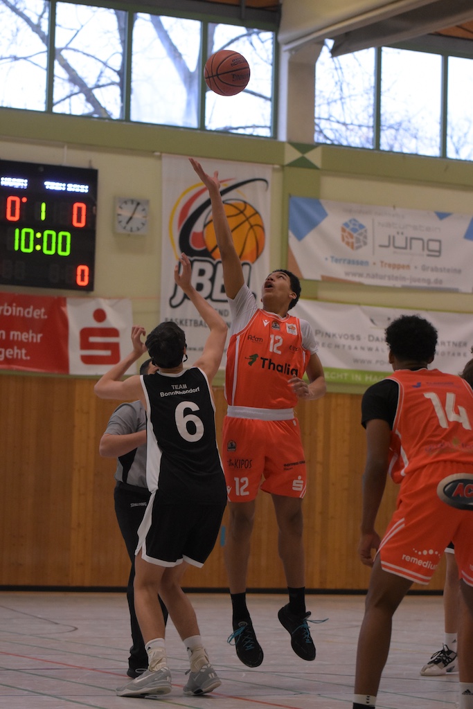 Zwei Basketballspieler springen beim Sprungball hoch, beide wirken konzentriert und entschlossen