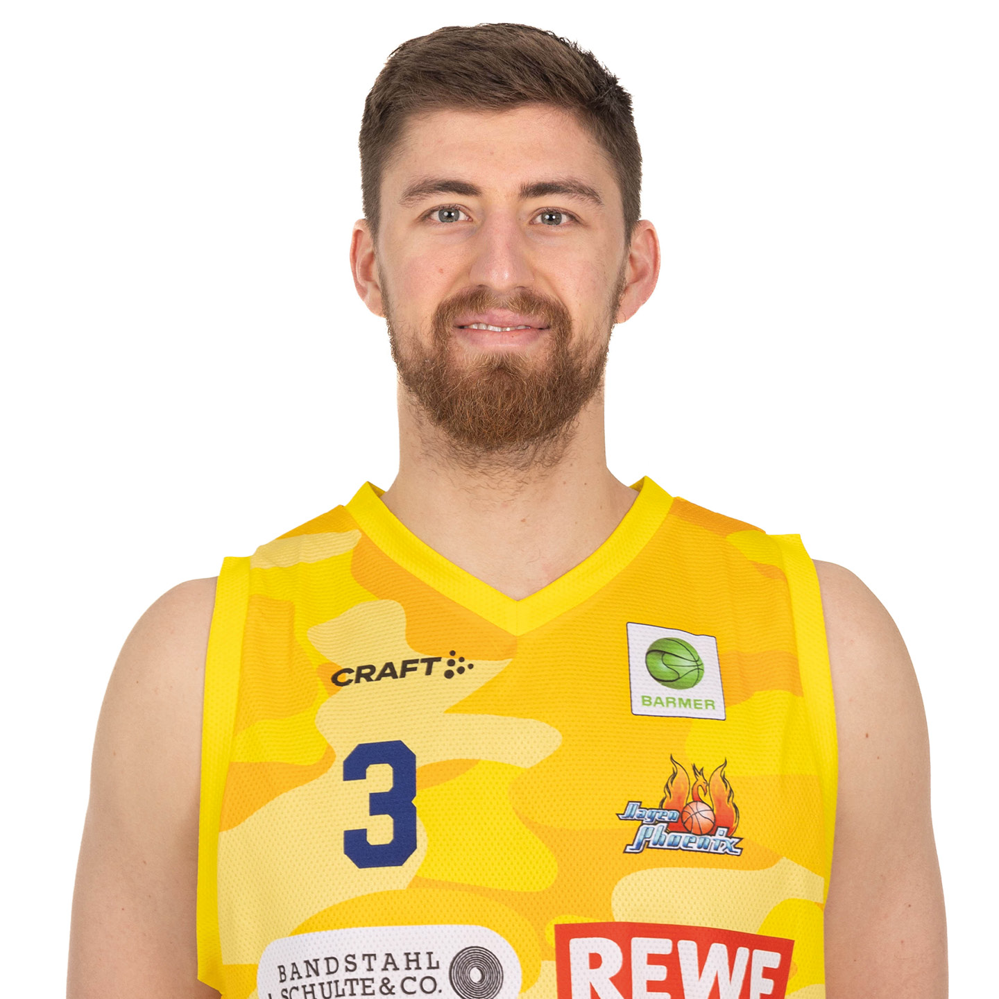 Ein junger Mann mit braunem Haar und Bart lächelt freundlich im gelben Basketballtrikot