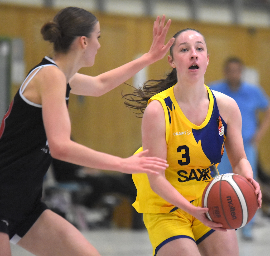 Eine junge Frau im gelben Basketballtrikot konzentriert sich mit dem Ball in den Händen