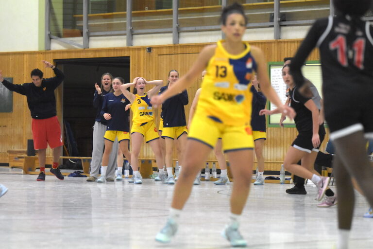 Mehrere Spielerinnen in gelben Basketballtrikots jubeln freudig am Spielfeldrand