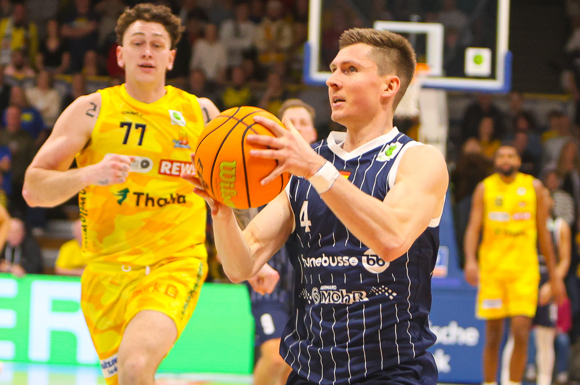 Ein Basketballspieler im dunkelblauen Trikot konzentriert sich auf einen Korbleger